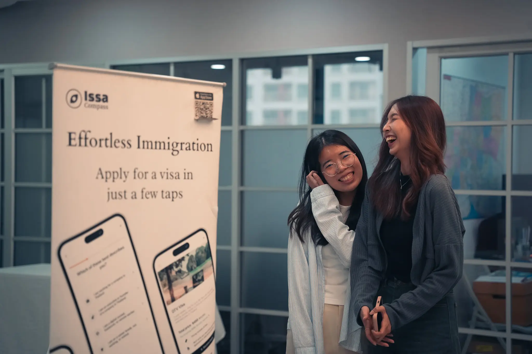 Two Issa Compass teammates laughing together in the office