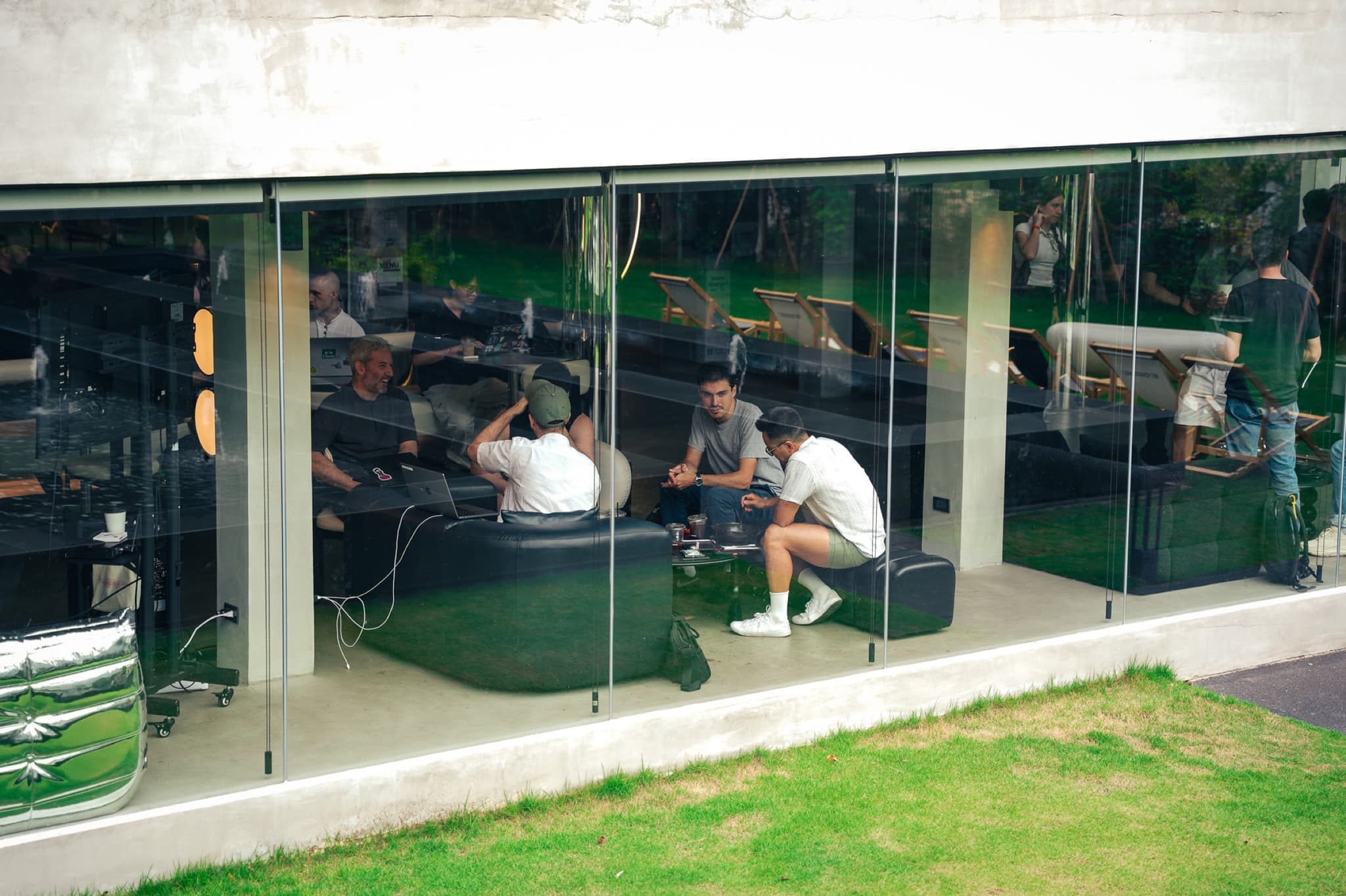 Builders coworking on black sofas, seen through the glass wall of UN:HOUR