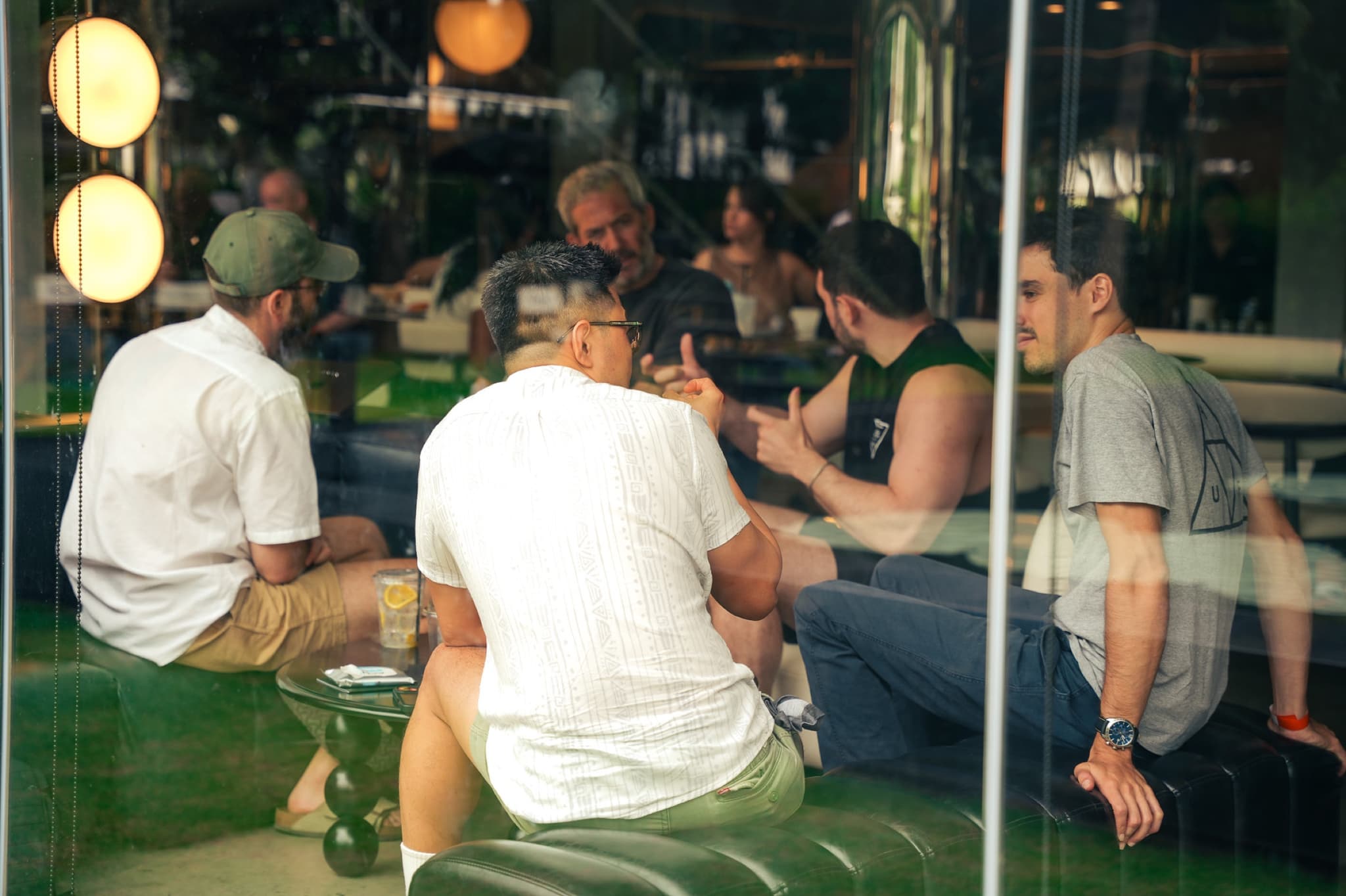 A group talking on the UN:HOUR sofas, seen through the garden glass