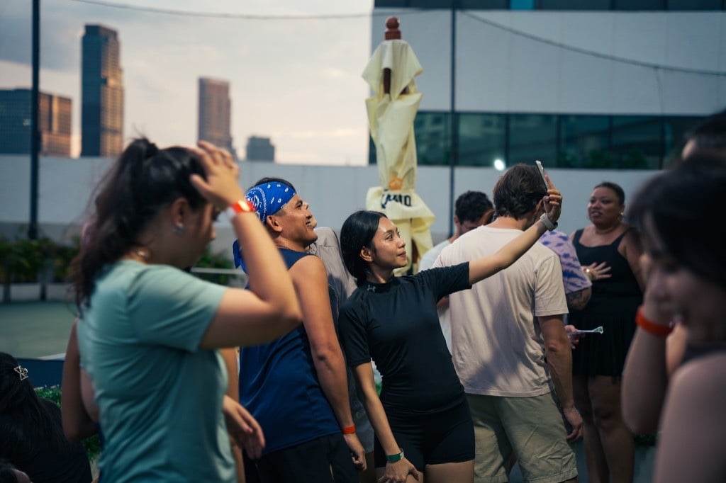 People gathering on a rooftop, one taking a selfie