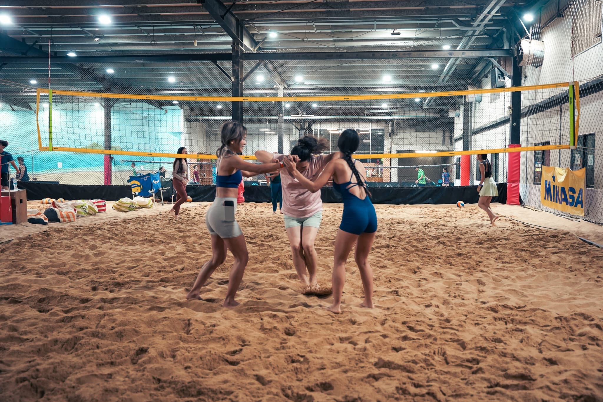 Three players in a huddle on the sand volleyball court