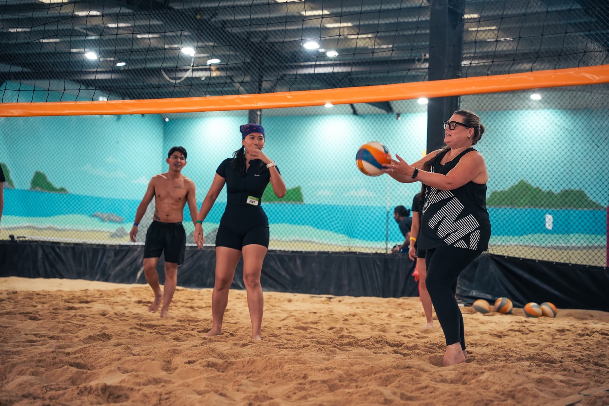 A player setting a volleyball on the indoor sand court